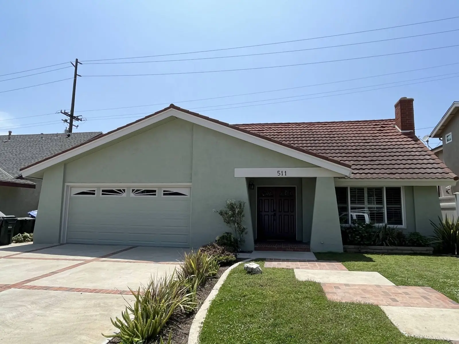 Ranch home after painting in soft sage with crisp white garage door