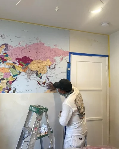 Painters finishing a hand-painted world map mural