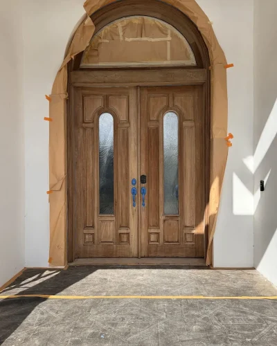 Arched double wood entry doors masked for refinishing
